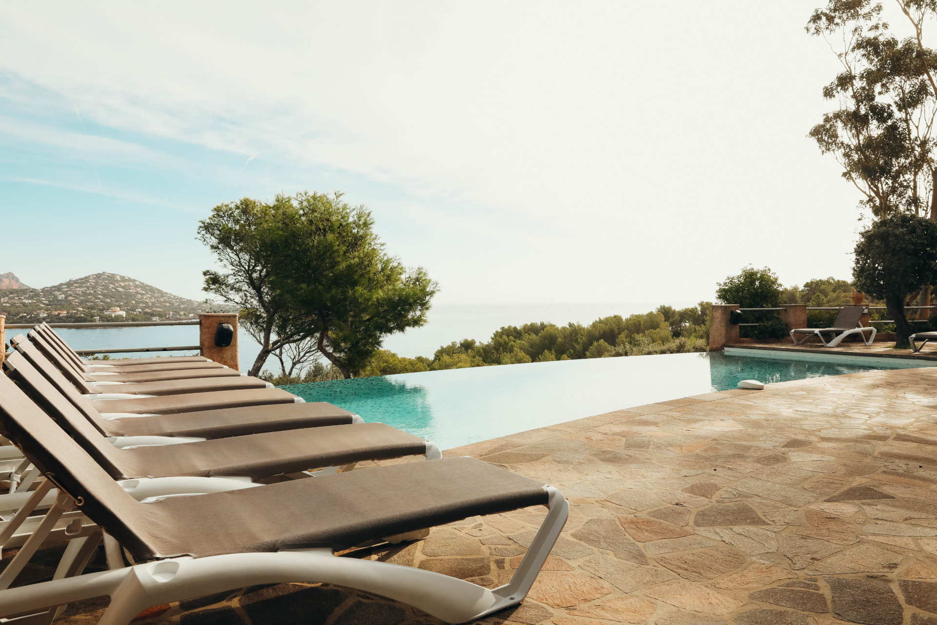 Transats au bord de la piscine à débordement face à la baie