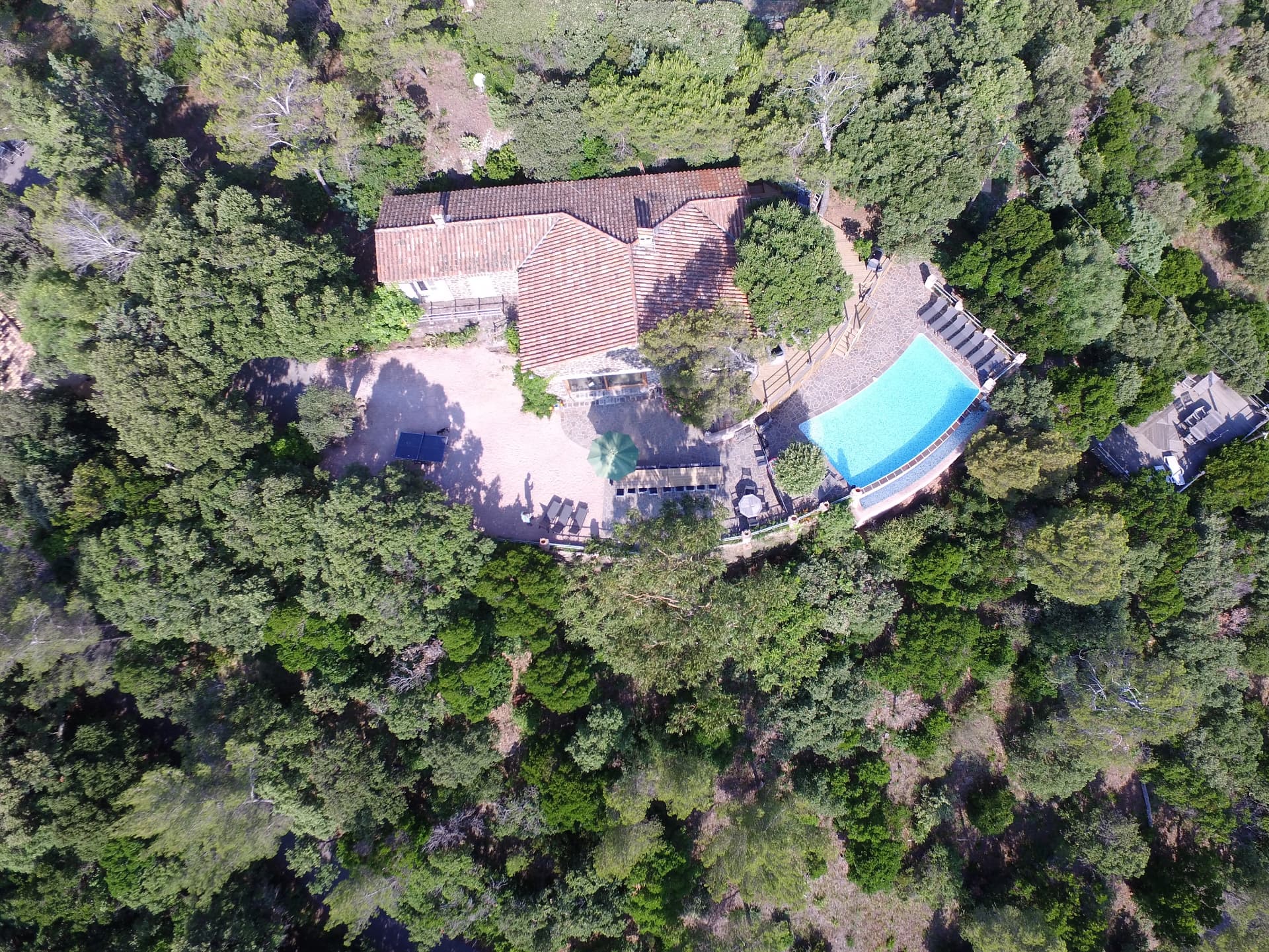 Vue aérienne à la verticale de la villa, sa piscine et la forêt alentour