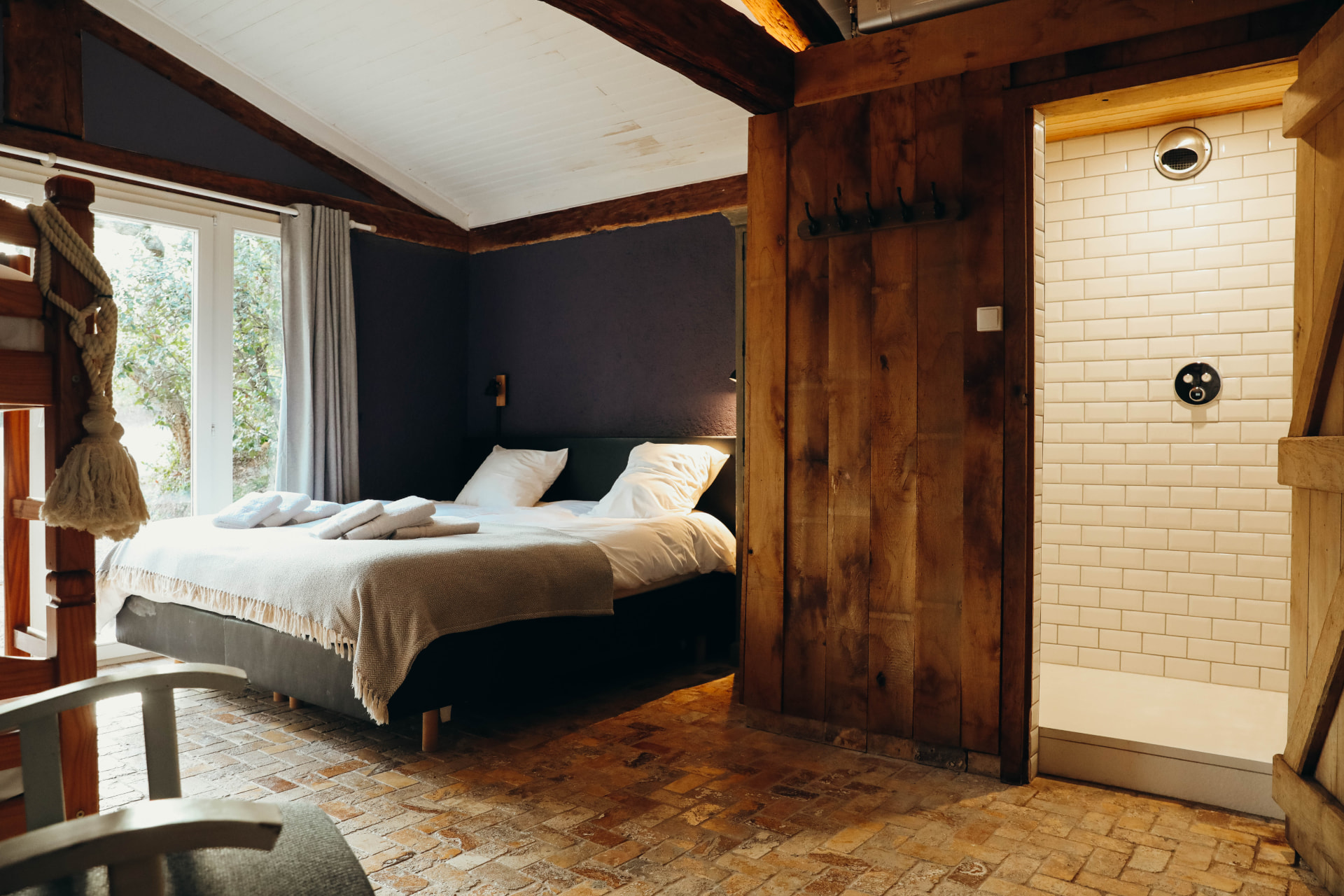Chambre aux poutres anciennes, sol en pierre et douche adjacente