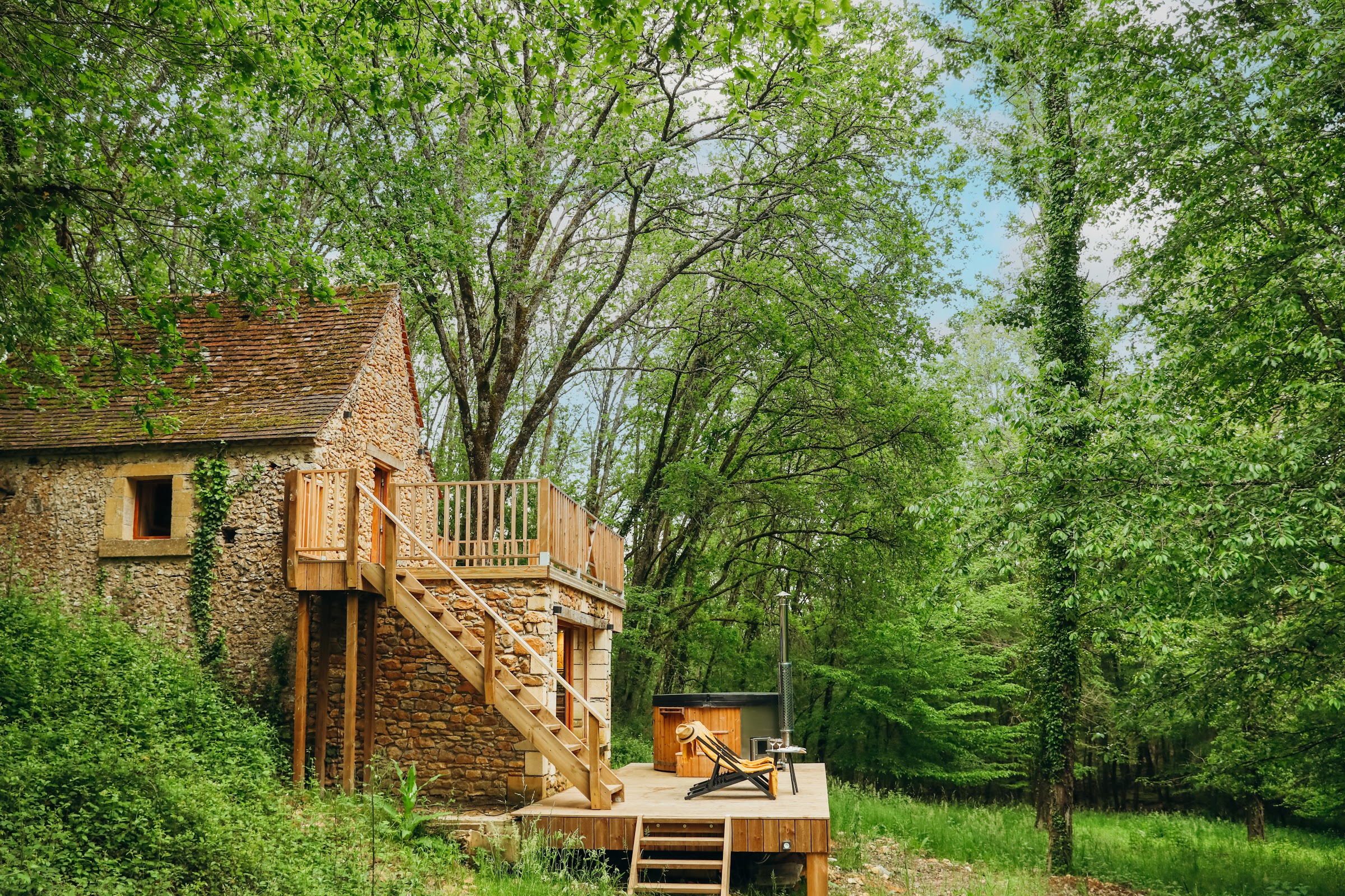 La bâtisse et son escalier extérieur en bois dans la clairière boisée