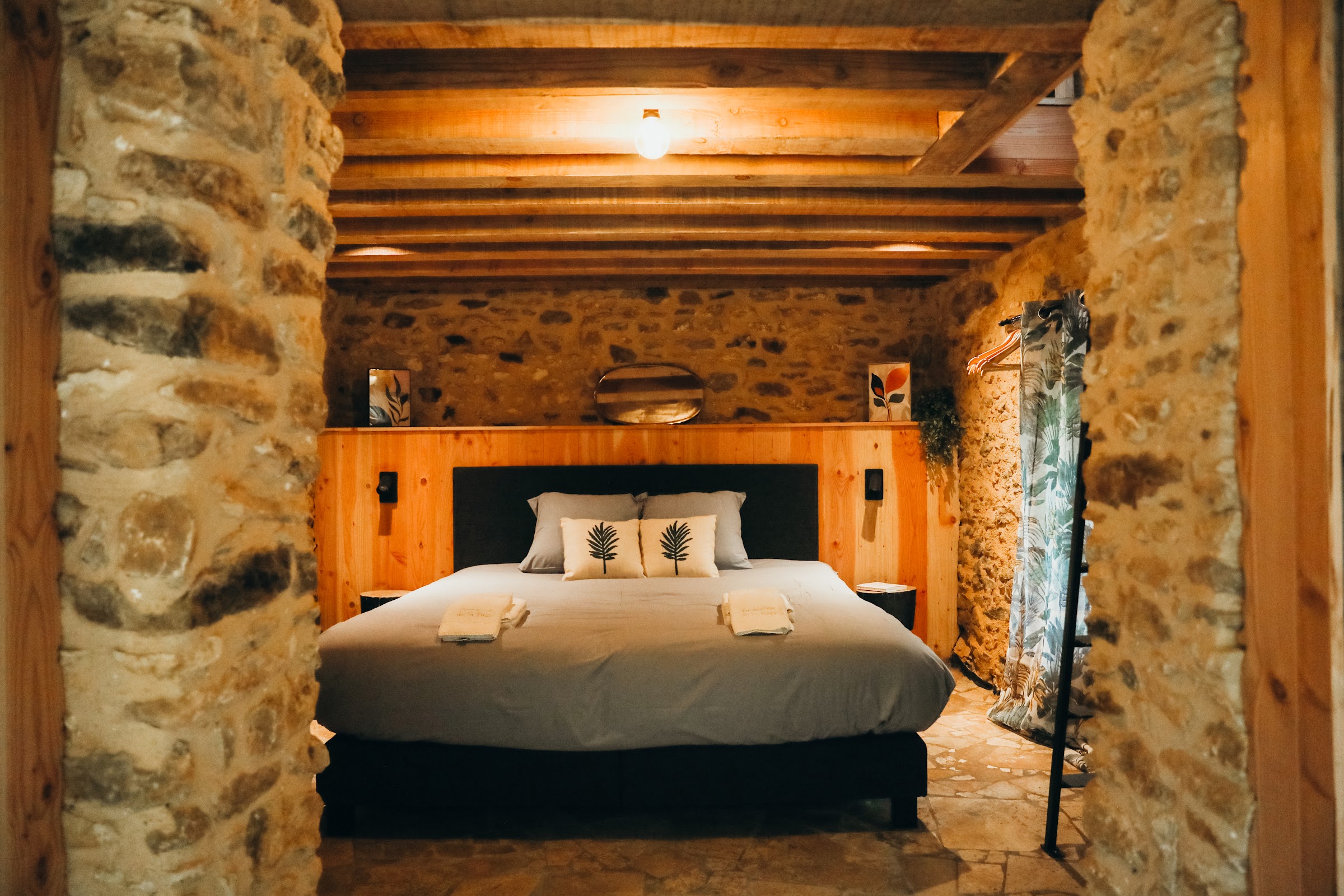 Chambre sous poutres avec murs en pierre et lit double