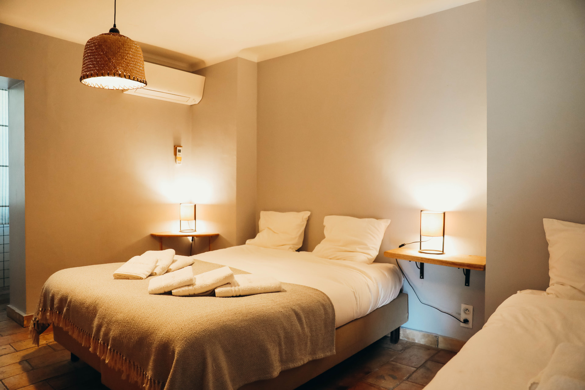 Chambre aux tons crème avec lampes de chevet et tomettes