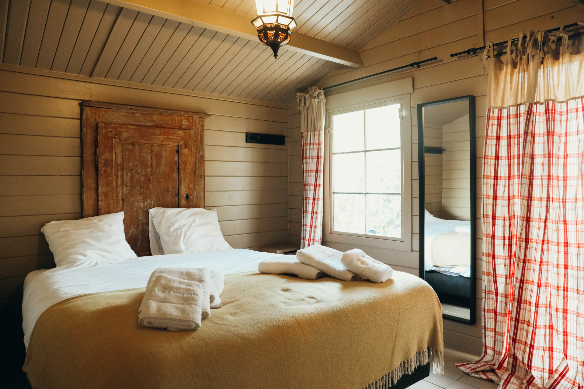 Chambre en bois clair avec linge blanc et vue sur la pinède