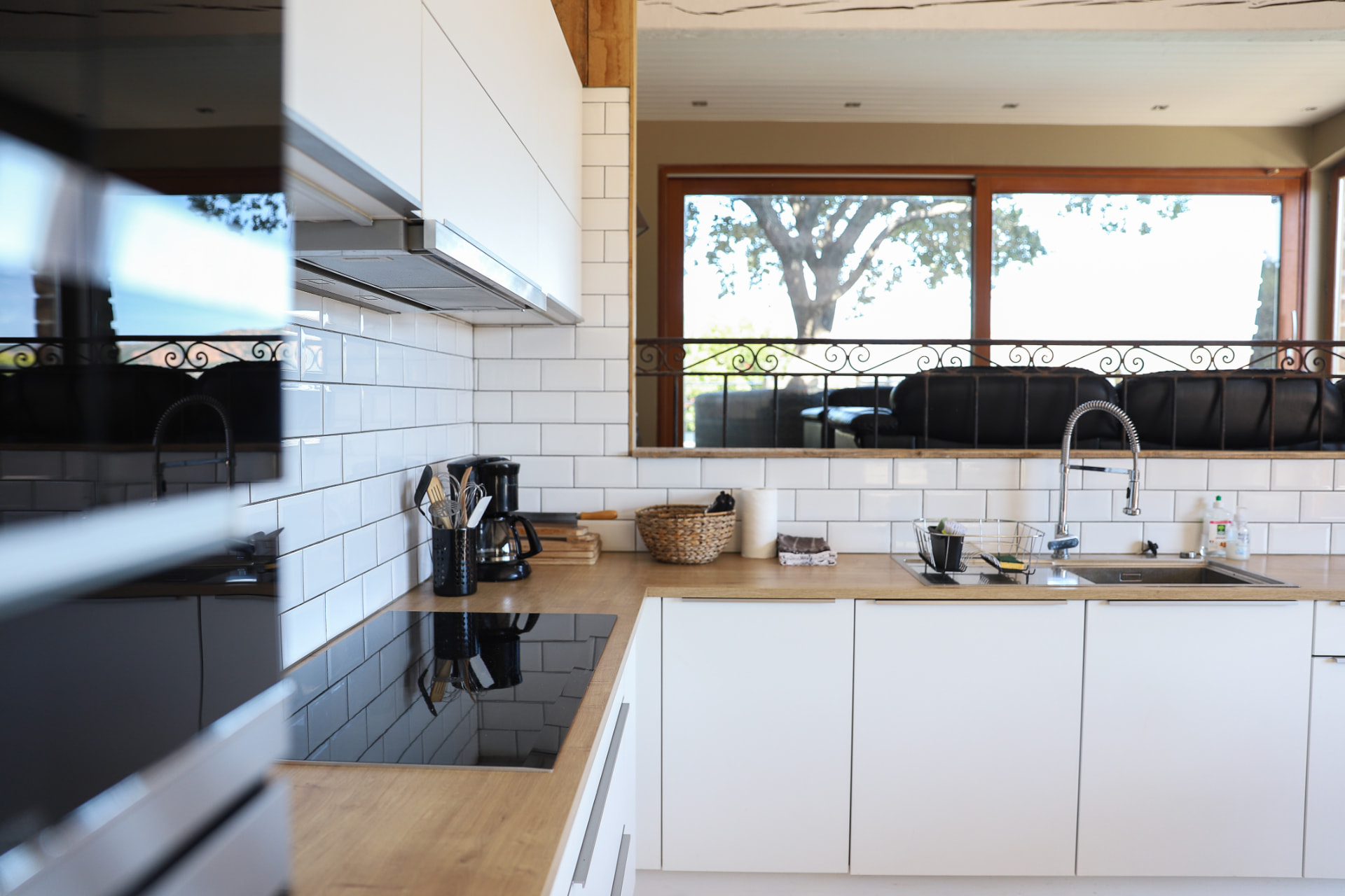 Cuisine équipée blanche avec plan de travail en bois ouvrant sur le salon
