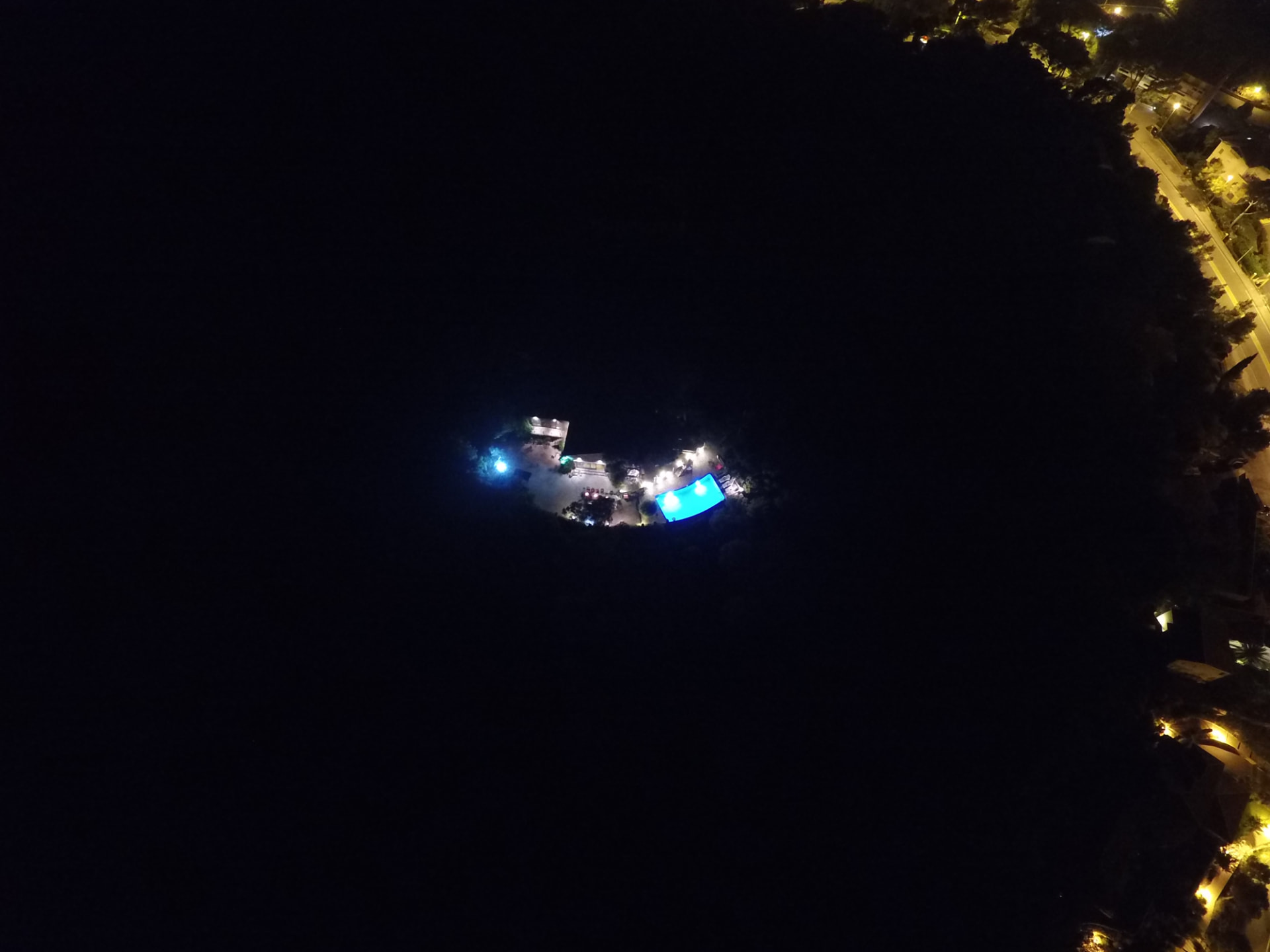 La propriété illuminée de nuit vue du ciel, piscine turquoise au cœur de la pinède