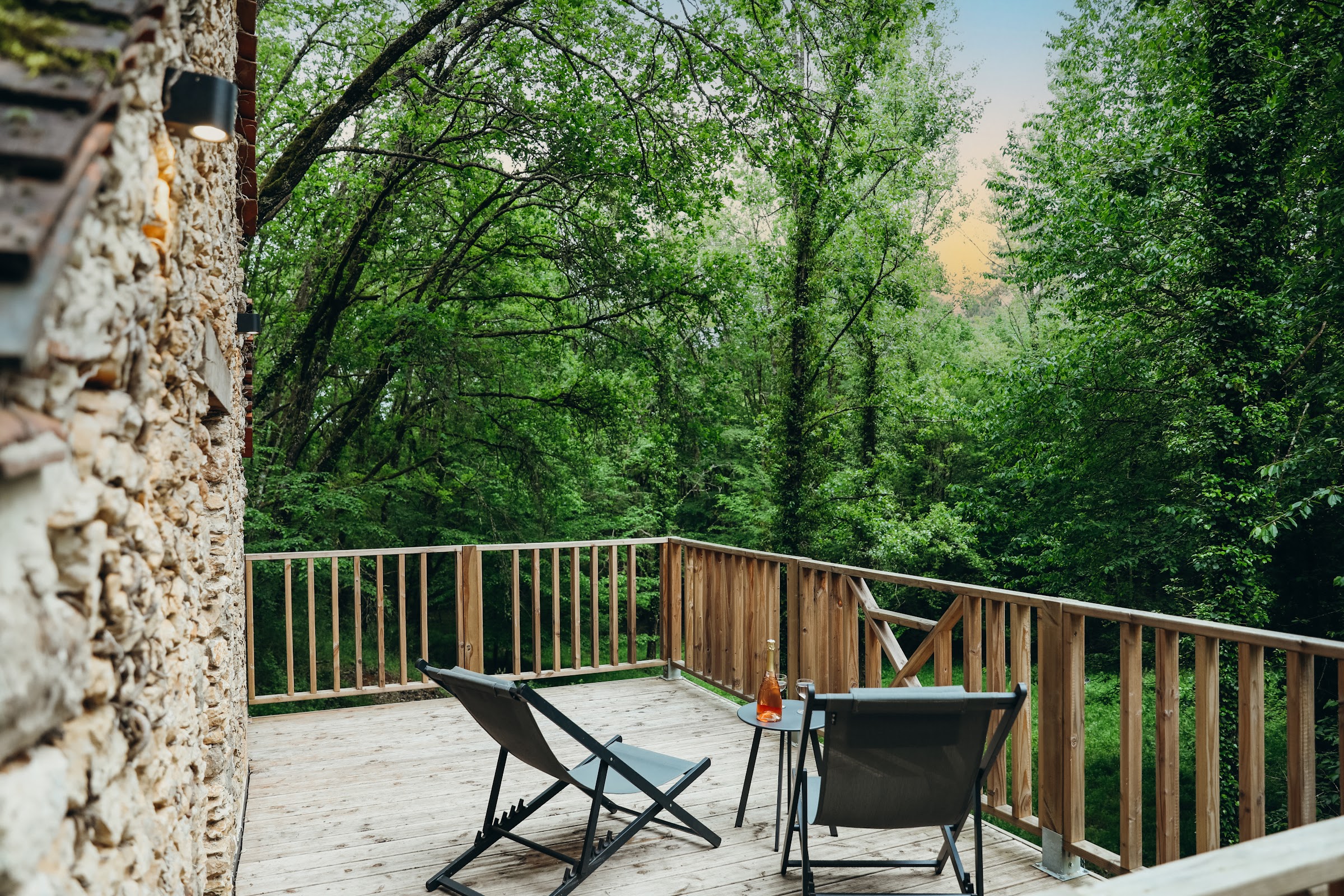 Façade en pierre et terrasse en bois ouverte sur la forêt