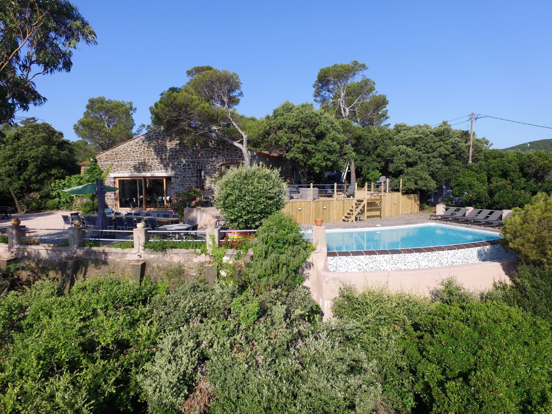 La villa en pierre, ses terrasses et la piscine vues depuis les hauteurs