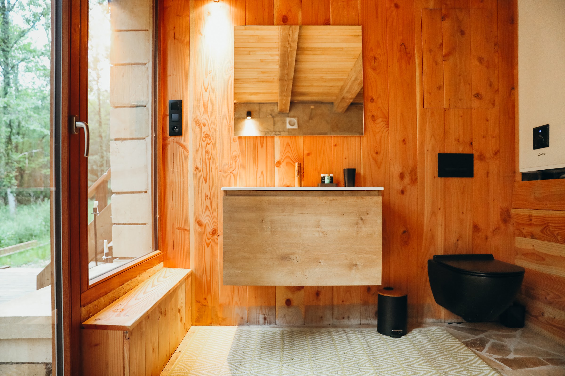 Salle de bain habillée de bois avec vasque et vue sur la forêt